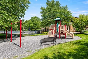 A playground with a red swing set and a green and red play structure.